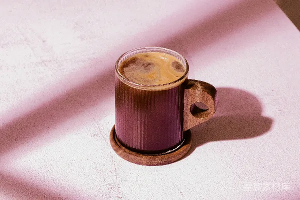 高清摄影 玻璃杯中盛放着咖啡，置于木制 coaster 上。