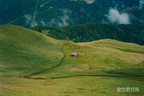 小木屋坐落在一片草丛繁茂的山地景观中。
