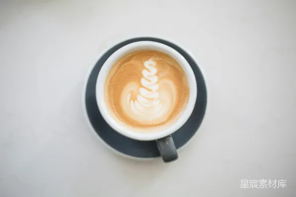 高清摄影 灰白相间的陶瓷咖啡杯，上面有咖啡拉花艺术
