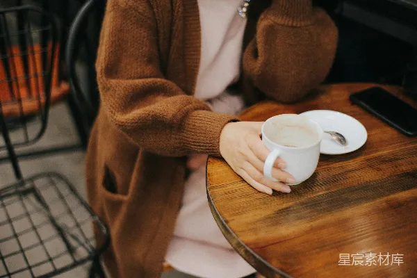 高清摄影 女人坐在椅子上，手里拿着一个白色的 mug。