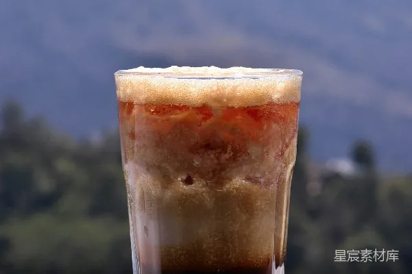 高清摄影 桌子上一杯酒旁边放着一座山。