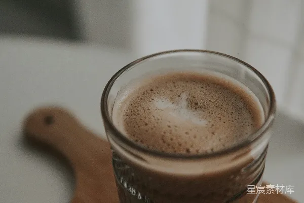高清摄影 棕色木桌上有一个棕色液体的透明酒杯