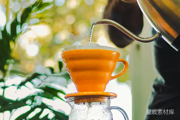 高清摄影 一个人往一个玻璃 pitcher 中倒橙汁。