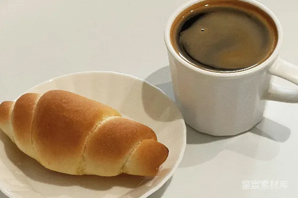 高清摄影 一个白色的盘子上放着一片面包，旁边放着一杯咖啡。