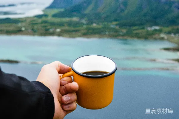 高清摄影 山顶上一个人拿着一杯咖啡。