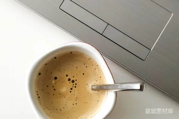 高清摄影 咖啡满到手的马克杯放在笔记本电脑旁边