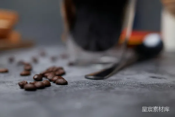 高清摄影 咖啡豆散落在一杯深色液体旁边。
