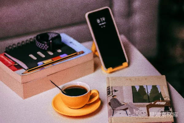 高清摄影 黑色的iPhone 5放在一本白色的书旁边，旁边是带托盘的咖啡杯。