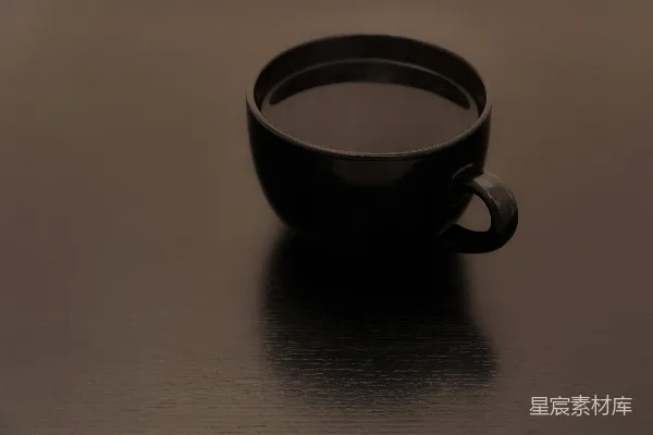 高清摄影 一个黑色的咖啡杯放在一个表面上。