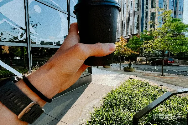 高清摄影 一只手拿着一杯咖啡站在建筑物前面