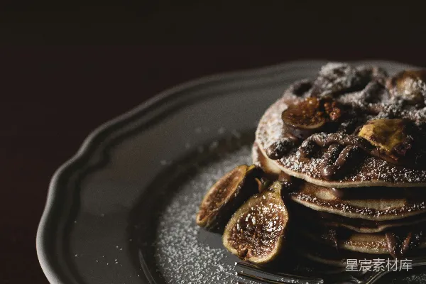 高清摄影 浅焦摄影：上面铺有香蕉片和 syrup 的 pancakes，放在灰色的盘子上。