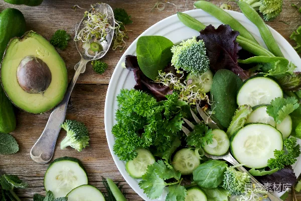 高清摄影 盘中切好的 broccoli 和 cucumber，旁边有一把灰色的不锈钢叉，靠近绿色的青椒、毛豆和牛油果果实。