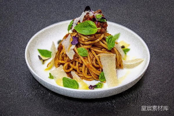 高清摄影 一只白盘子上面放着意大利面和蔬菜。