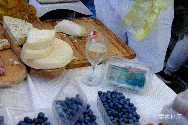 高清摄影 一个售卖奶酪、蓝莓、 strawberries 和白葡萄酒的市集小摊。