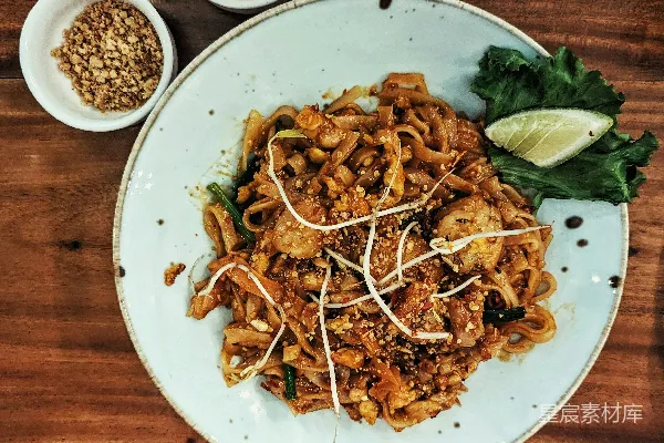 高清摄影 一块白色 plates 上面放着面条和肉。