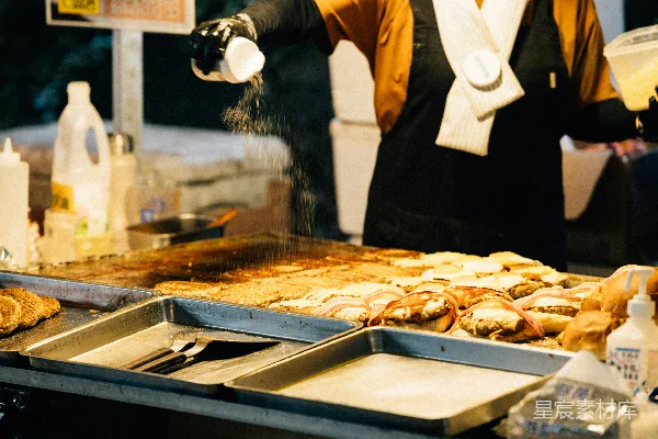 高清摄影 夜幕下，摊贩在平顶烤架上为食物调味。