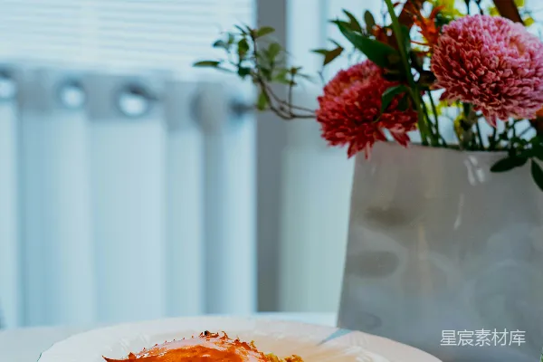 高清摄影 一只装在白盘中的螃蟹菜肴，上面点缀着花朵。