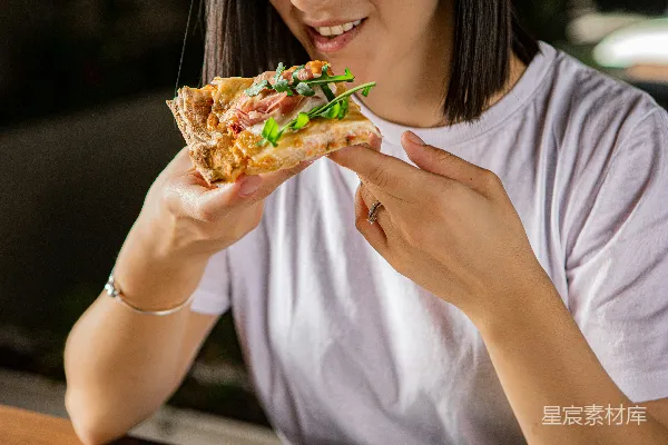 高清摄影 一位女性在吃一块披萨。