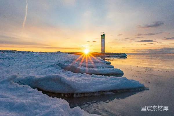 白天白雪覆盖的地上有一座黑白相间的灯塔