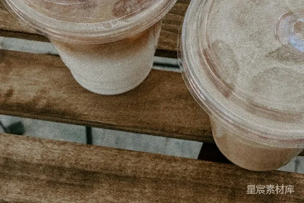 两张木质长凳上放置着两杯冰咖啡。