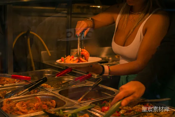 高清摄影 一个女人在自助餐台上切着一盘食物。