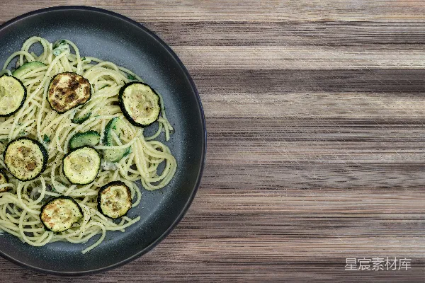 高清摄影 一盘带着西葫芦的 spaghetti 沉在木质桌子上