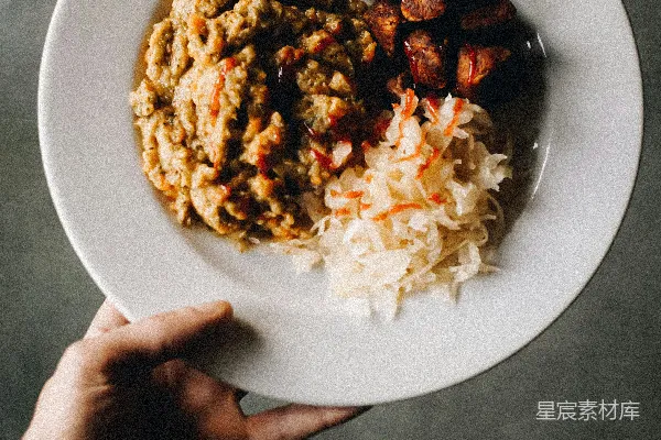 高清摄影 桌子上站着一个人，手里拿着一盘食物。