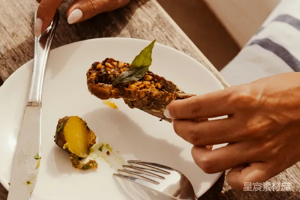 高清摄影 一个人正在用叉子和刀吃烧烤食物。