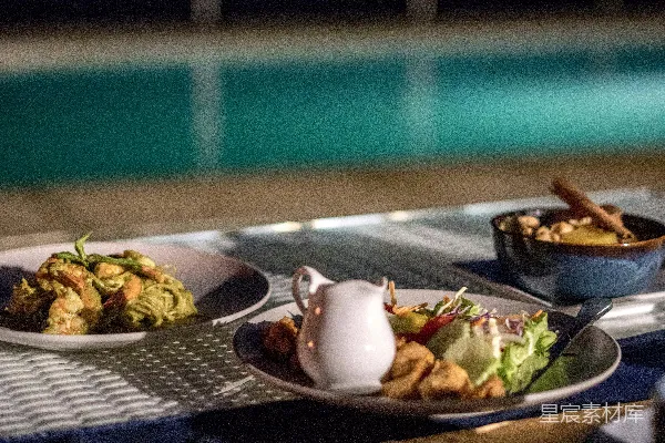 高清摄影 餐桌旁摆放着餐盘的食物靠近游泳池