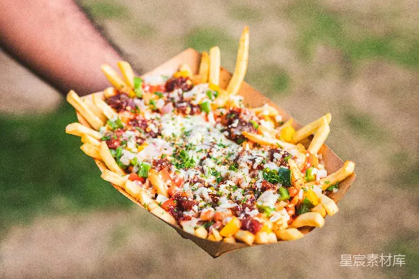 高清摄影 手持一盘带有奶酪和其他配料的薯条的人