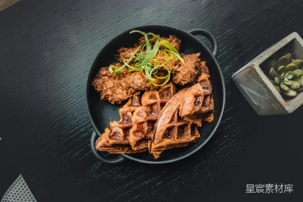 高清摄影 黑铁锅附近的炸食旁边是瓦菲，旁边是绿色的仙人掌植物。