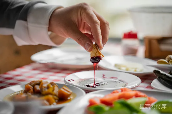 高清摄影 手将面包蘸在盘中的一道深色酱汁中。
