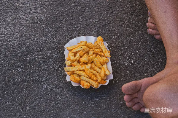 高清摄影 一个人在暗色沥青上吃炸薯条。
