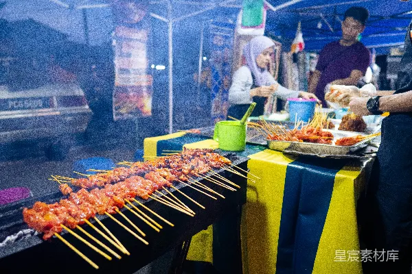 高清摄影 一群人在桌子周围站着，桌子上有烤串的食物