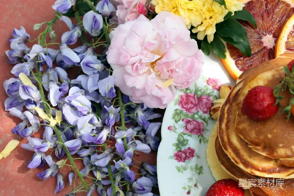 高清摄影 一张桌子上有 Pancakes、草莓和花朵的盘子