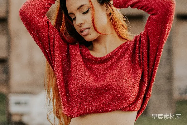 红色毛衣的女人在白天的绿色草地田地里站立。