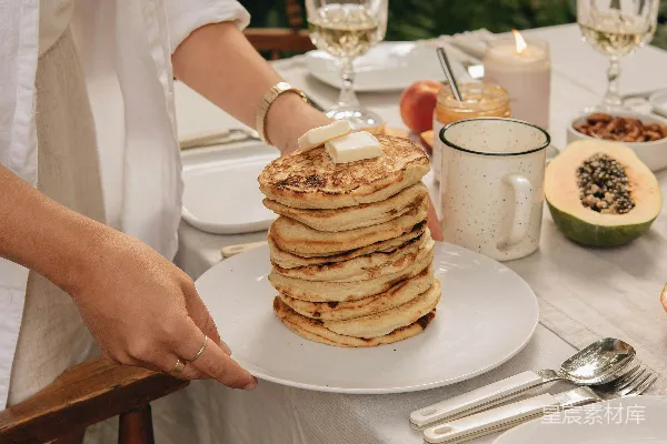 高清摄影 白裙女子手持白色陶瓷盘子，盘中有 Pancakes。