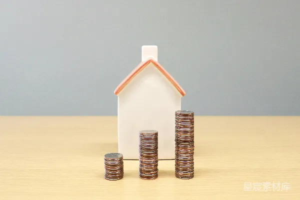 高清摄影 桌子上放着一幢房子和一堆堆的金币。
