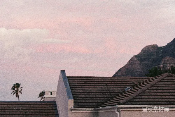 高清摄影 夕阳下，山峦与棕榈树下的房屋