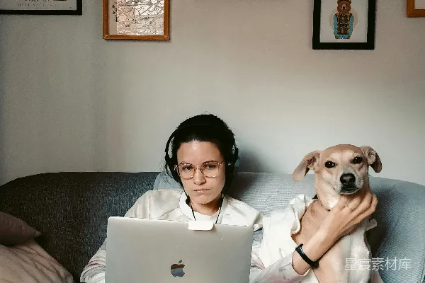 高清摄影 穿白色长袖衬衫的女人坐在灰色沙发上，旁边放着一台MacBook。