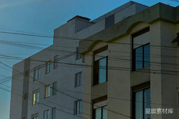 高清摄影 现代建筑在晴朗的天空下，头顶横跨着交错的电线。