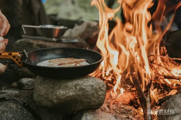 高清摄影 一个人在篝火上用平底锅做饭