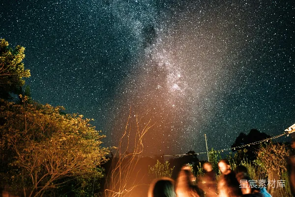 高清摄影 一群人围坐在篝火旁，夜空中满是星星。