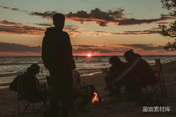 高清摄影 夕阳下，人们坐在水边的椅子上，剪影般地映衬在水面上。