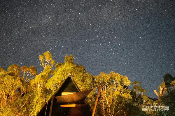 高清摄影 在星空下，绿色草地上有一座棕色木屋。