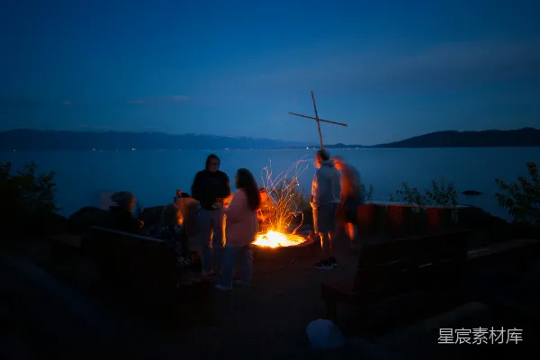 高清摄影 人们围着夜晚水边的篝火聚集在一起。