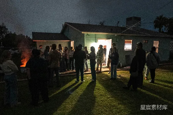 高清摄影 人们在夜晚聚集在一所房子外面。