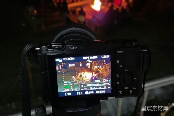 高清摄影 三脚架上的相机在夜晚拍摄营火周围的人。