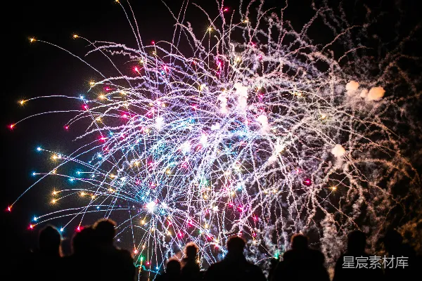 高清摄影 夜空中，五彩缤纷的烟花在剪影人群上方绽放。