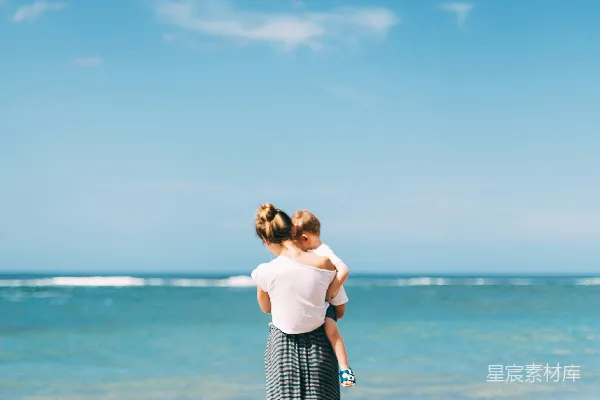 高清摄影 在海边，一位女士抱着一个蹒跚学步的孩子。
